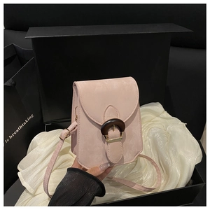 Détail d'un petit sac bandoulière hexagonal rose avec boucle en bois sur soie blanche