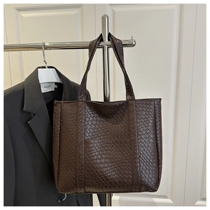 Detailed view of the dark brown woven texture and solid handle of the large tote bag