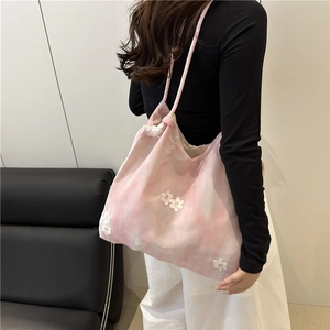 Pink pleated handbag with white lace floral accents worn over a shoulder for summer fashion