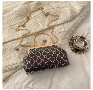 Detailed macro view of black sequin handbag with rainbow fish scale pattern and metal handle