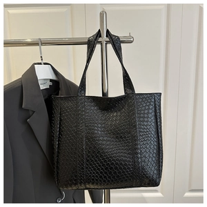 Detail of the black woven texture on the large PU leather tote bag hanging in a studio