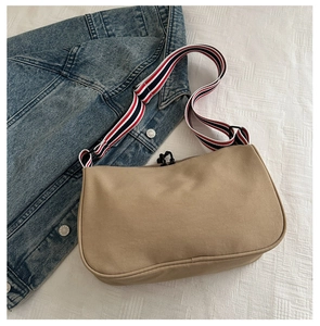 Dettaglio della tracolla a righe tricolore su una borsa tote kaki in tela casual