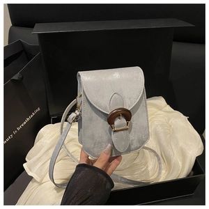 Détail d'un petit sac bandoulière gris clair avec boucle circulaire en grain de bois