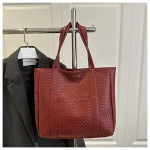 Detail of dark red woven leather tote bag with large capacity and shoulder strap