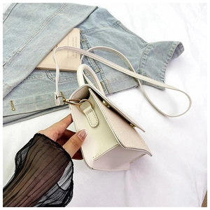 Detail of white woven texture handbag with golden hardware and slender shoulder strap