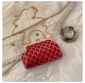 Detail of red sequin evening bag with gold scale pattern and metallic frame handle