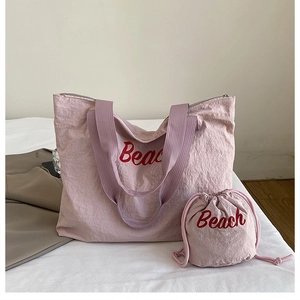 Détail de l'ensemble sac fourre-tout en nylon rose et pochette avec lettrage Beach