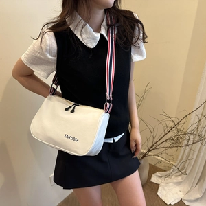 Borsa a tracolla in tela con cinturino a righe e logo FANYISSA indossata da una modella