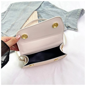Close-up of off-white crossbody bag with double magnetic snaps and black lining detail