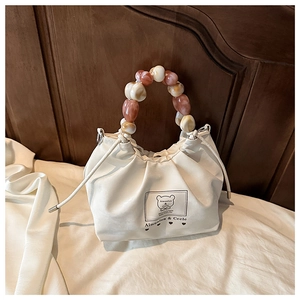 Close-up of white pleated cloud bag with colorful marble beads handle and bear logo detail
