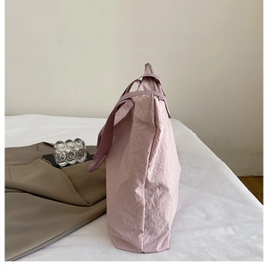 Détail du sac cabas en nylon rose clair montrant la texture douce et le zip latéral