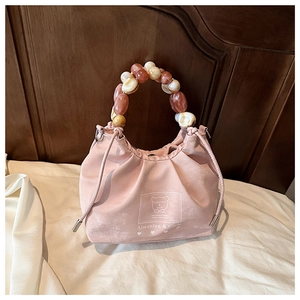 Detail of pink drawstring bucket bag with colorful acrylic beaded handle and logo