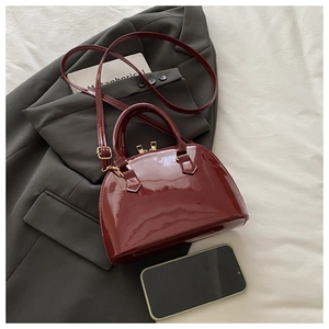 Detail of burgundy shell bag with glossy patent leather finish and gold zipper