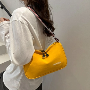 Dettaglio borsa tote in tela gialla con tracolla a strisce e doppia zip