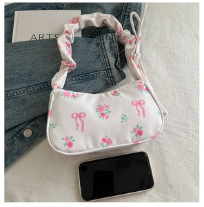 Floral print bag with pleated strap and pink rose patterns beside a smartphone for scale