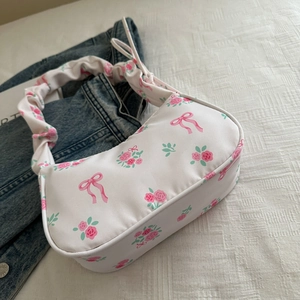 Detail of white hobo bag with pink rose patterns and stylish scrunchie shoulder strap