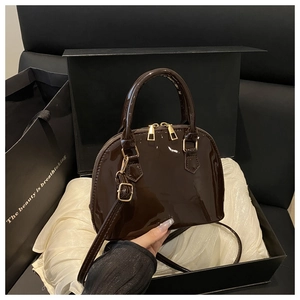 Deep brown patent leather shell bag shown with premium gift box and dust bag