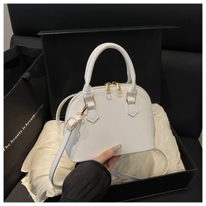 Close-up of a white patent leather shell bag inside a luxury gift box with satin lining