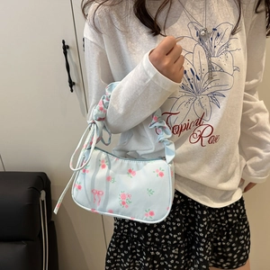 Detail of light blue floral baguette bag with pink ribbon bow and ruched shoulder strap