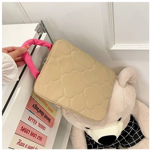 Quilted beige computer bag with pink handles shown in a cozy home setting with decor