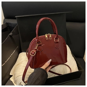 Detail of wine red patent leather shell bag inside a luxury gift box with golden zippers