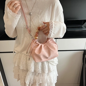 Pink dumpling bag with amber resin beaded handle and logo displayed on a model
