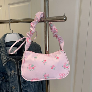 Close-up of pink floral shoulder bag with rose patterns and ruched cloud strap