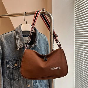 Dettaglio borsa tote caffè con tracolla larga a righe e stampa del logo minimalista