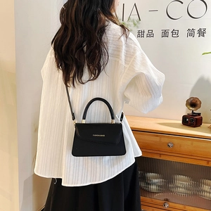 Minimalist black leather handbag for women in stylish indoor setting with shoulder strap