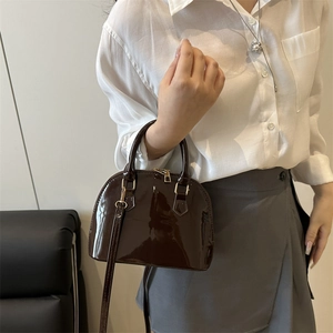 Elegant dark coffee patent leather shell bag with gold hardware for crossbody wear