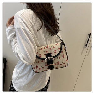 Close-up of stylish cherry print canvas shoulder bag with black leather strap and buckle