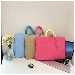 Detailed view of quilted laptop bags in blue, pink, and khaki with clover patterns