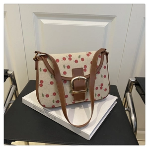 Detail of cherry print canvas shoulder bag with brown leather trim and gold metal clasp