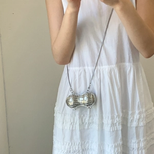Gros plan d'un mini sac en forme de cacahuète argenté avec strass et chaîne métallique
