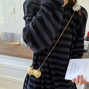 Vue détaillée d'un mini sac doré en forme de cacahuète avec une fine bandoulière chaîne