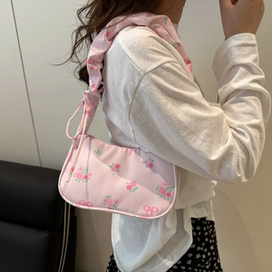 Pink floral shoulder bag with rose prints and pleated handle shown on model
