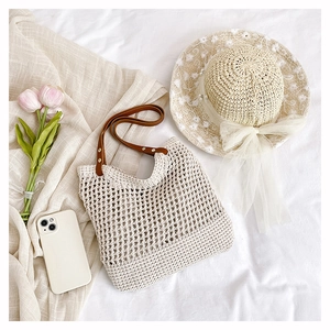 Close-up of a hollow woven straw shoulder bag with elegant lace floral sun hat