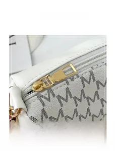 Close-up of golden metal zipper and monogram letter print on white textured leather bag