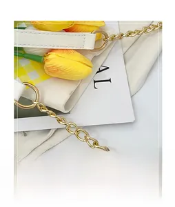 Detail of white textured leather handbag with gold metal ring and thick chain strap
