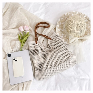 Detail of hollow crochet tote bag featuring brown leather straps and gold metal rivets