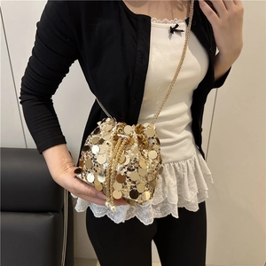 Close-up of golden sequin bucket bag with metal chain strap and pearl drawstring detail