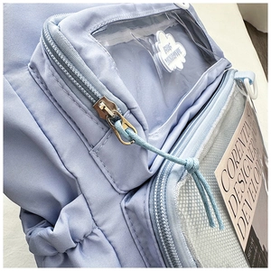 Close-up of light blue backpack detail featuring transparent PVC pocket and cloud decor