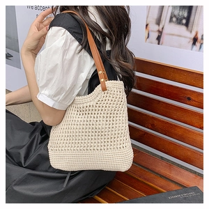 Close-up of cream crochet tote bag featuring woven texture and brown leather handles