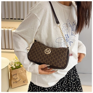 Brown monogram crossbody bag featuring gold M logo and chain strap shown on model