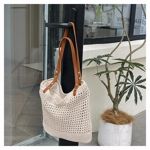 Macro detail of cream hollow woven tote bag with brown leather straps and metal rivets