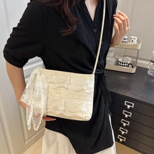 Detail of elegant ivory lace tote bag featuring a large decorative side bow and shoulder strap