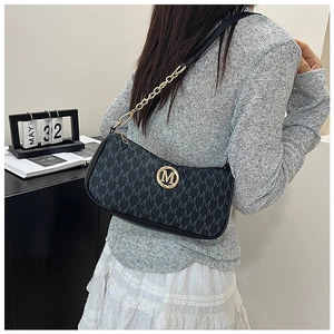 Detail of black monogram shoulder bag with gold metal logo and leather chain strap