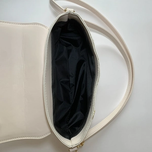 Internal view of cream shoulder bag showing spacious main compartment and inner pocket