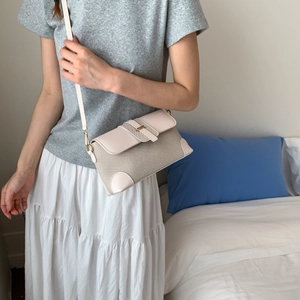 Detail view of beige woven crossbody bag with leather trim and gold hardware on model