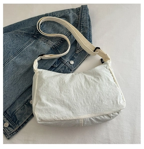 Close-up of white wrinkled nylon tote bag texture with adjustable strap on denim